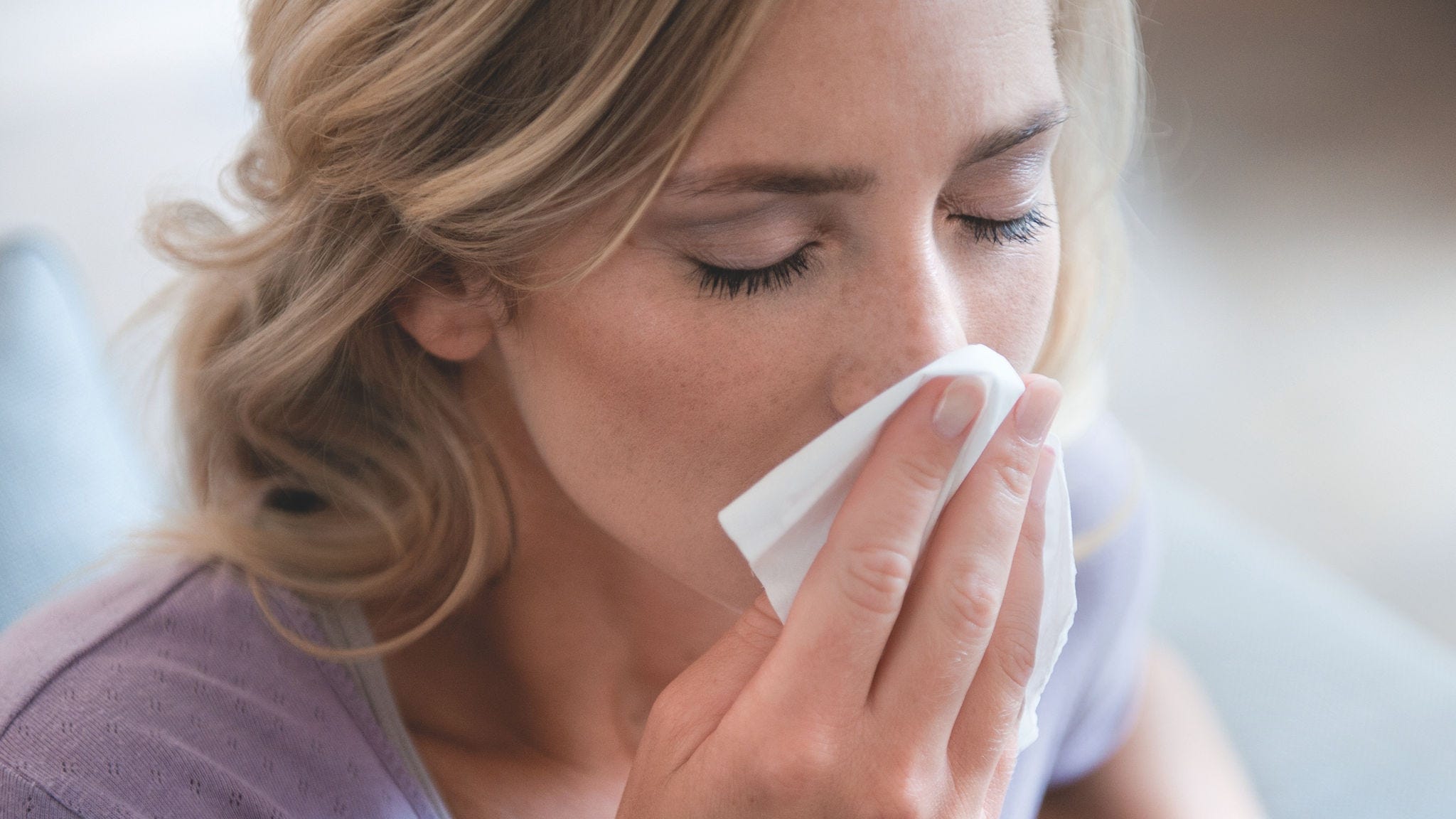 Femeie suflându-și nasul din cauza alergiei la polen