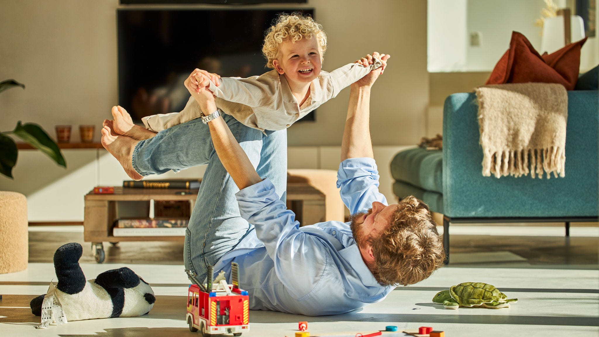 Tata și copilul său se joacă fericiți împreună și se bucură de căldura încălzirii prin pardoseală