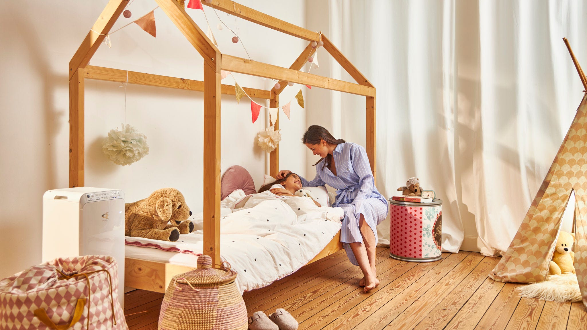 Mamă culcându-și copilul în locuința lor sănătoasă datorită purificatorului de aer Daikin din camera copiilor