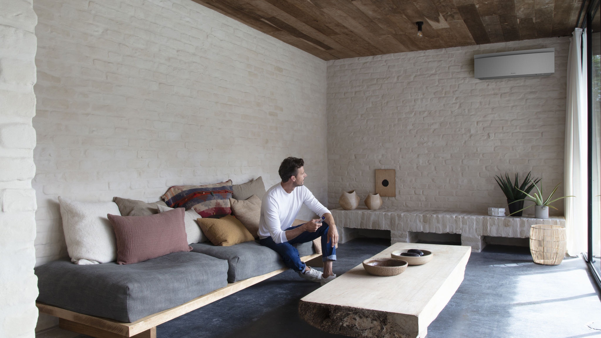 Bărbat controlând aparatul de aer condiționat din camera de zi cu o telecomandă