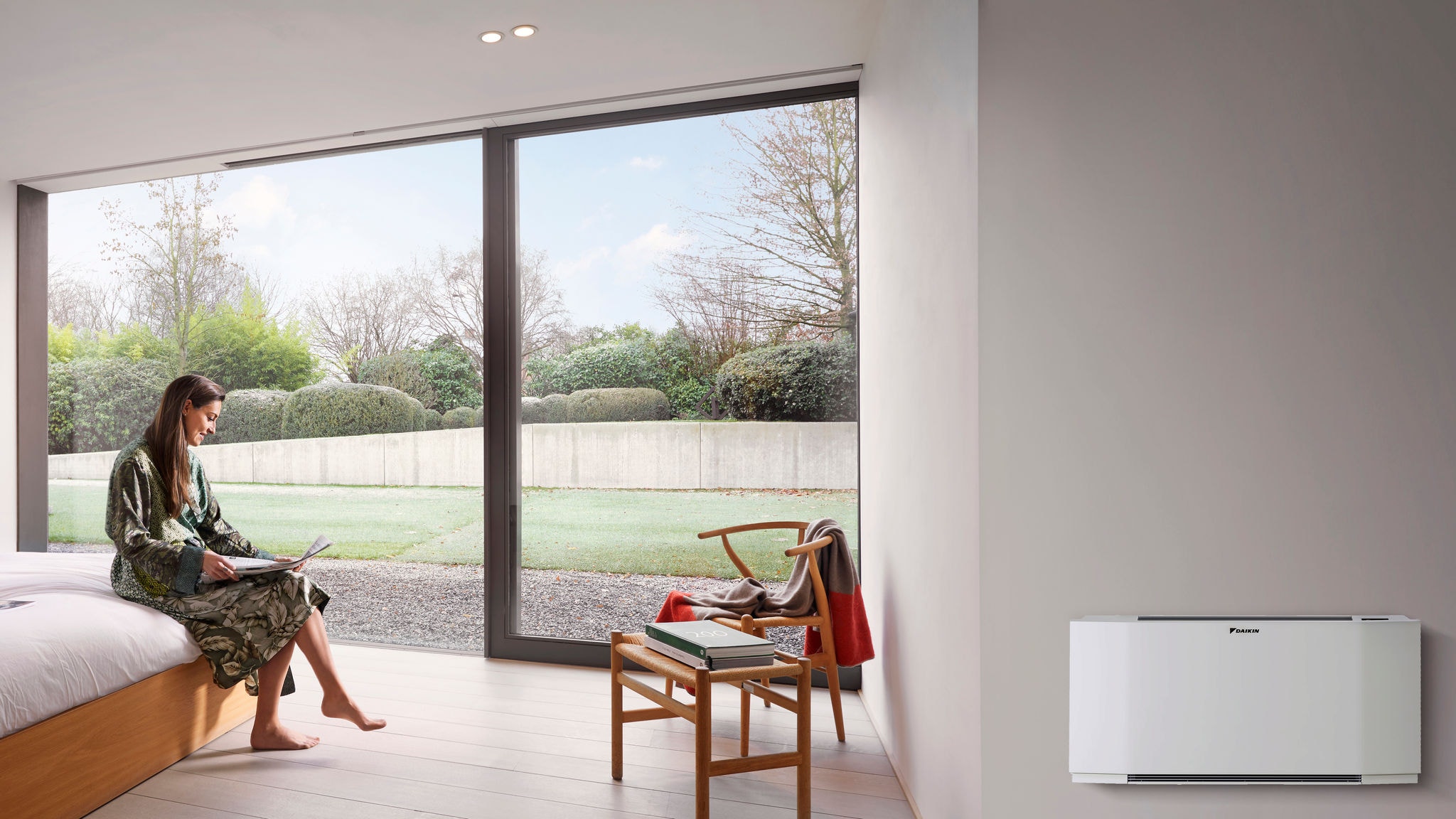 Woman reading newspaper in her room with a Daikin product