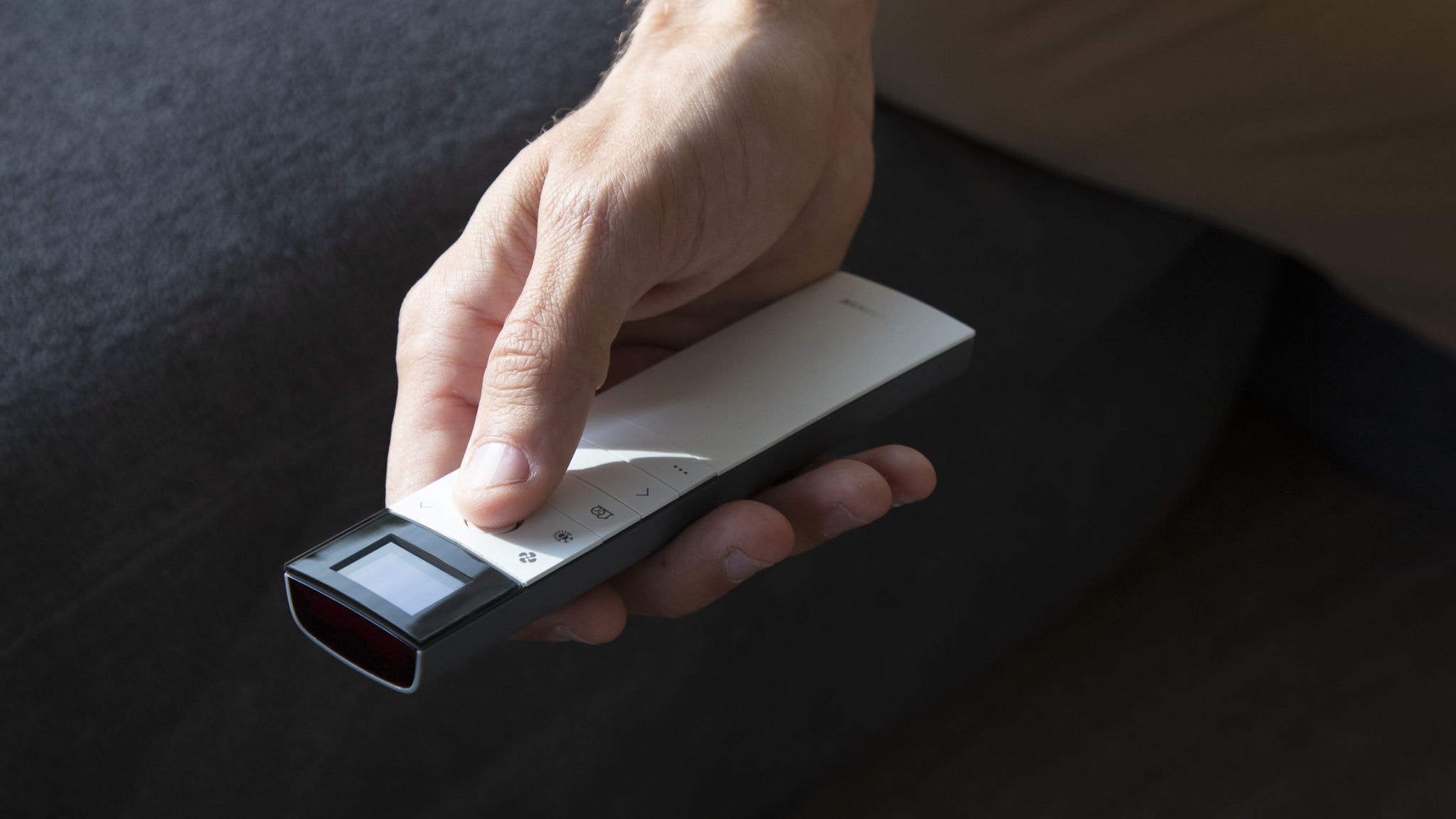 Bărbat controlând aparatul de aer condiționat din camera de zi cu o telecomandă