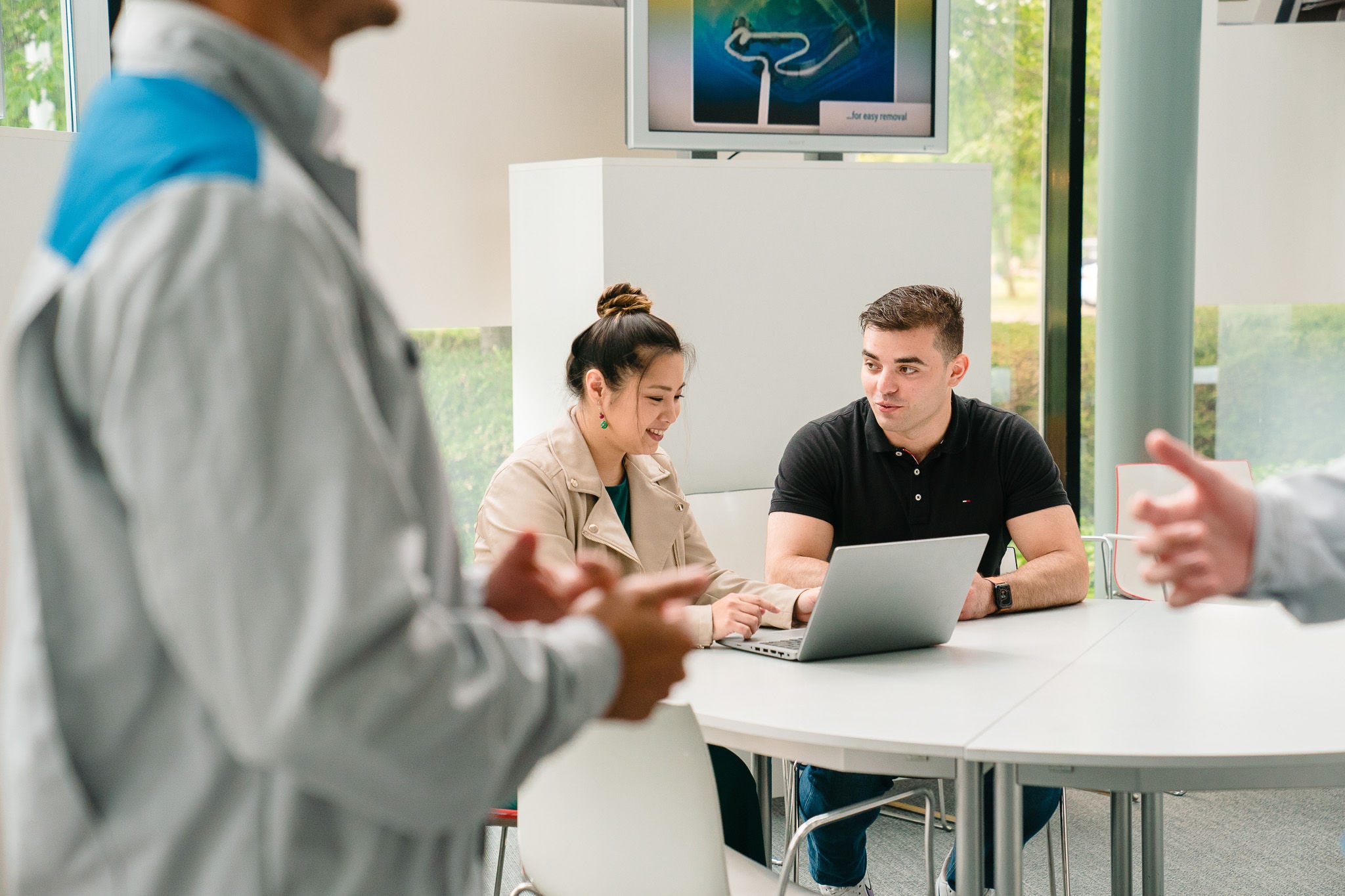 O femeie care explică ceva de pe laptop unui bărbat