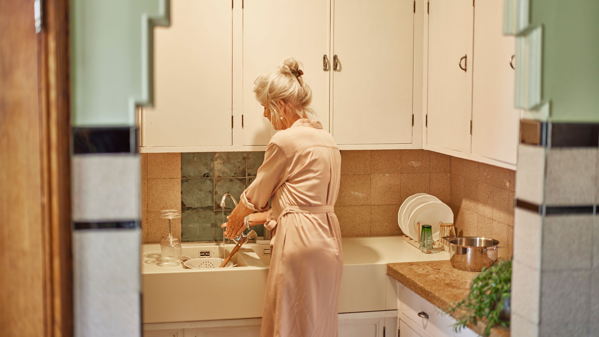 Femeie care spală vase cu apă caldă furnizată de Multi Split