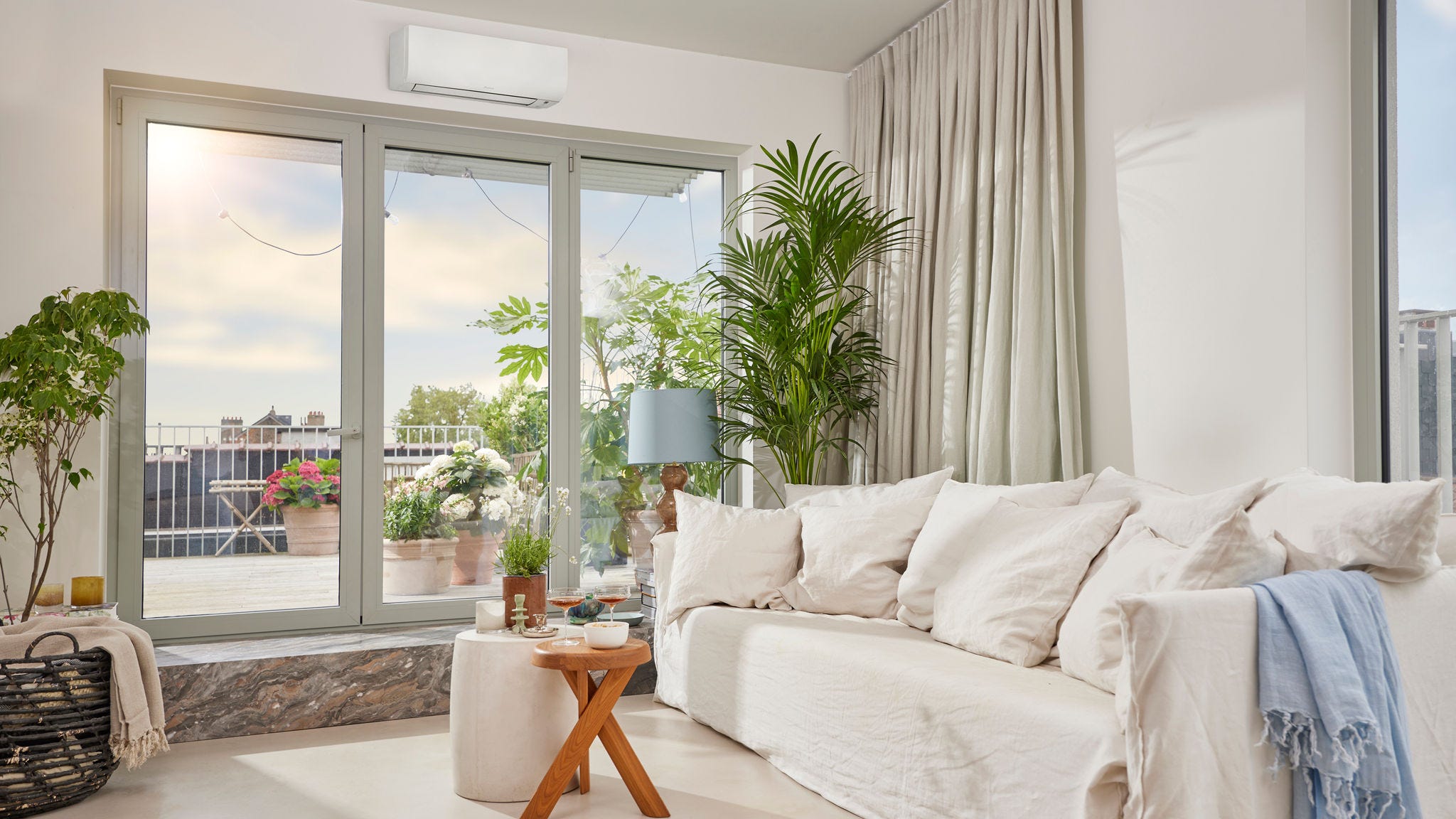 O încăpere luminoasă și aerisită, cu o pompă de căldură aer-aer albă, discretă, de perete, care asigură atât încălzire, cât și răcire