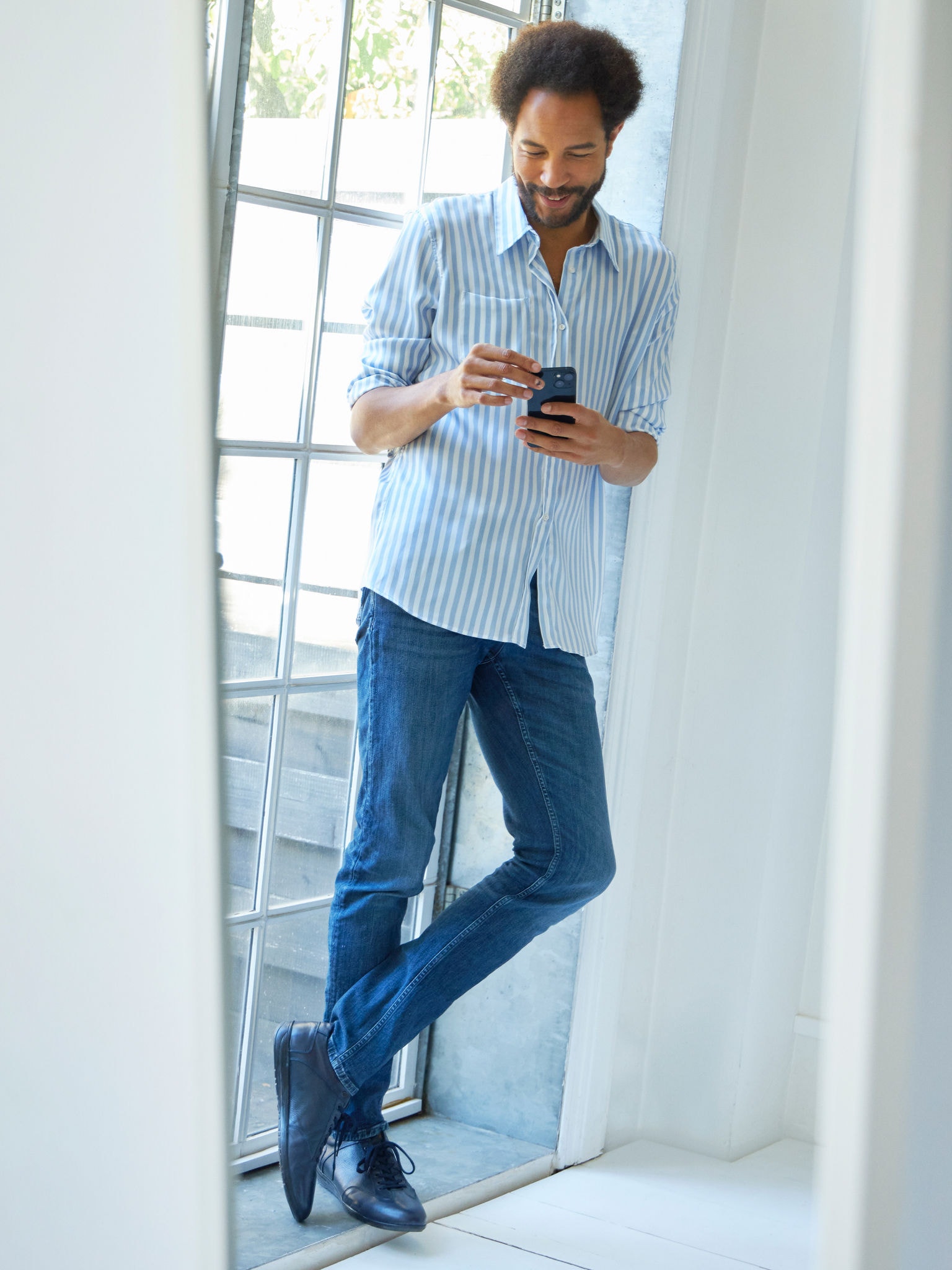 Bărbat stând în apropierea unei ferestre observând aparate de aer condiționat în centrul virtual de experiențe pe smartphone