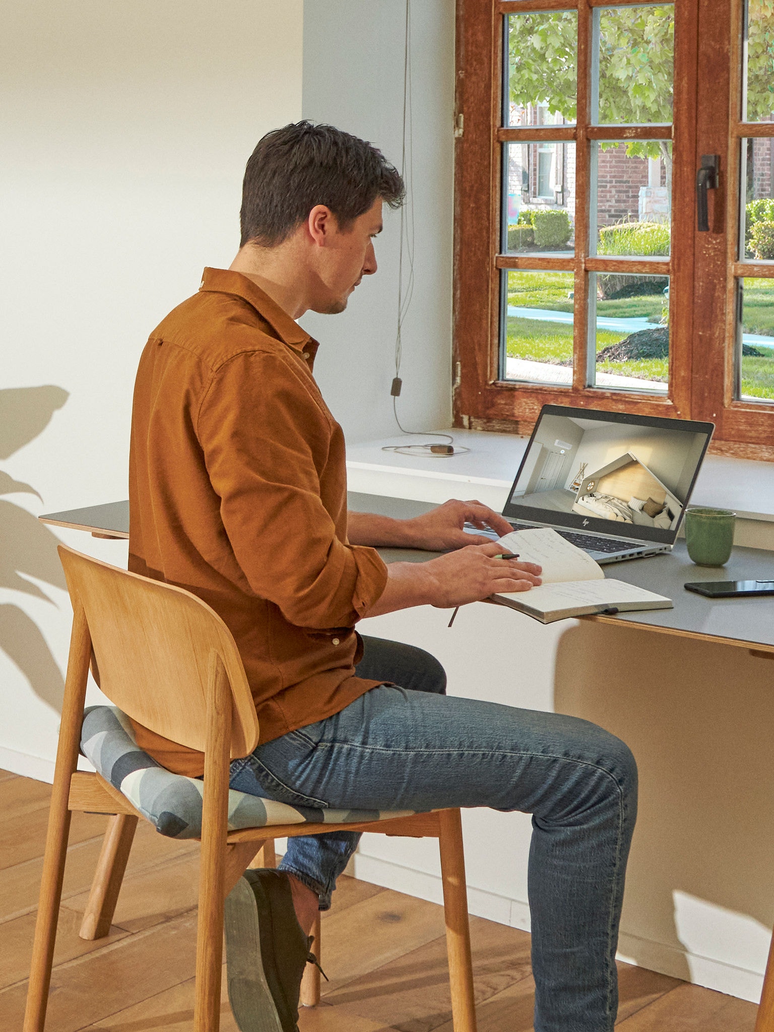 Bărbat stând în apropierea unei ferestre și observând aparate de aer condiționat în centrul virtual de experiențe pe laptop