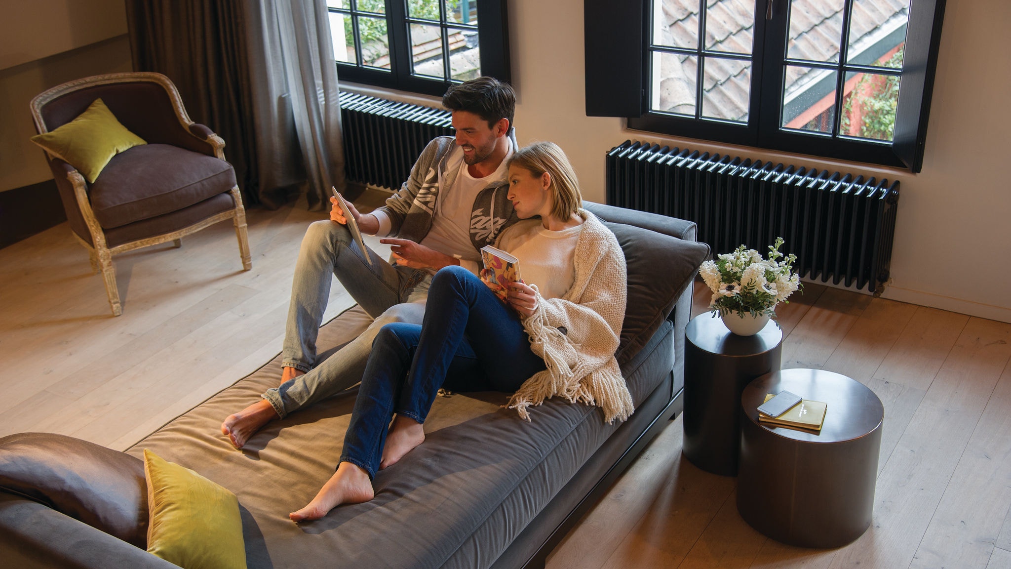 Cuplu relaxându-se pe canapea și urmărind ceva pe tabletă