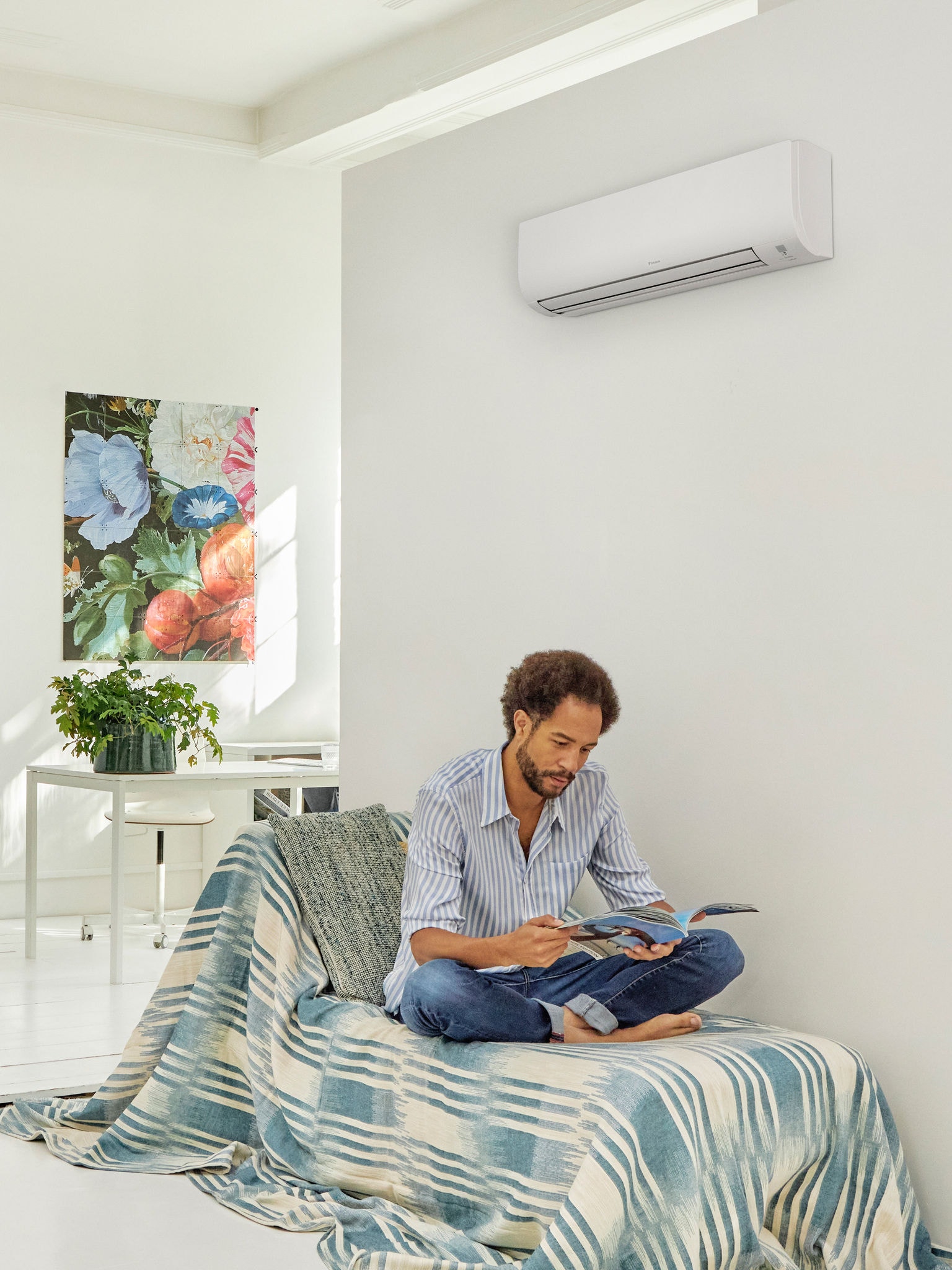 Bărbat citind într-un spațiu luminos și modern, cu o pompă de căldură montată pe perete, ilustrând confortul și eficiența energetică a tehnologiei pompei de căldură, care a beneficiat de schemele de subvenții oferite de guvern