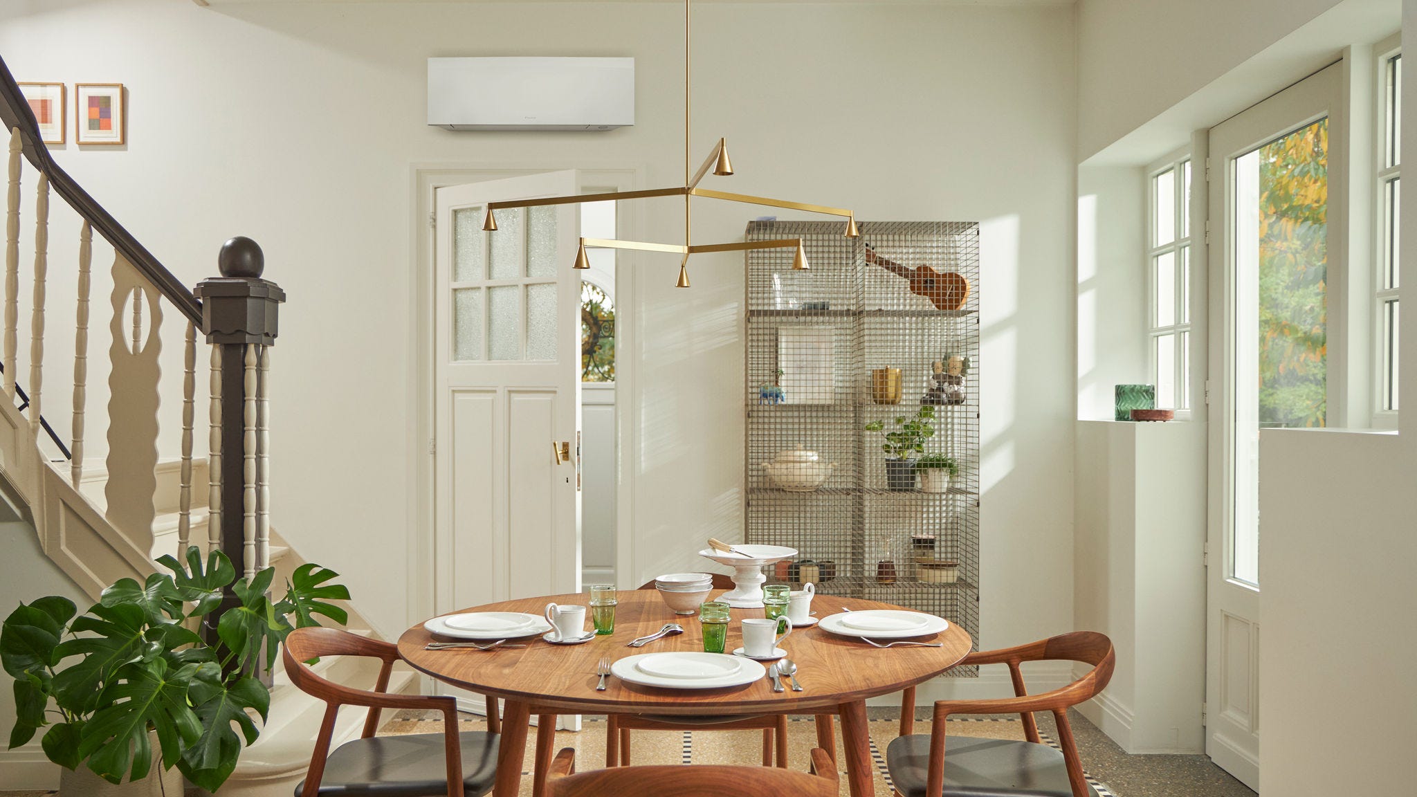 Cameră cu fereastră mare, masă din lemn și o soluție de climatizare de perete de culoare neagră