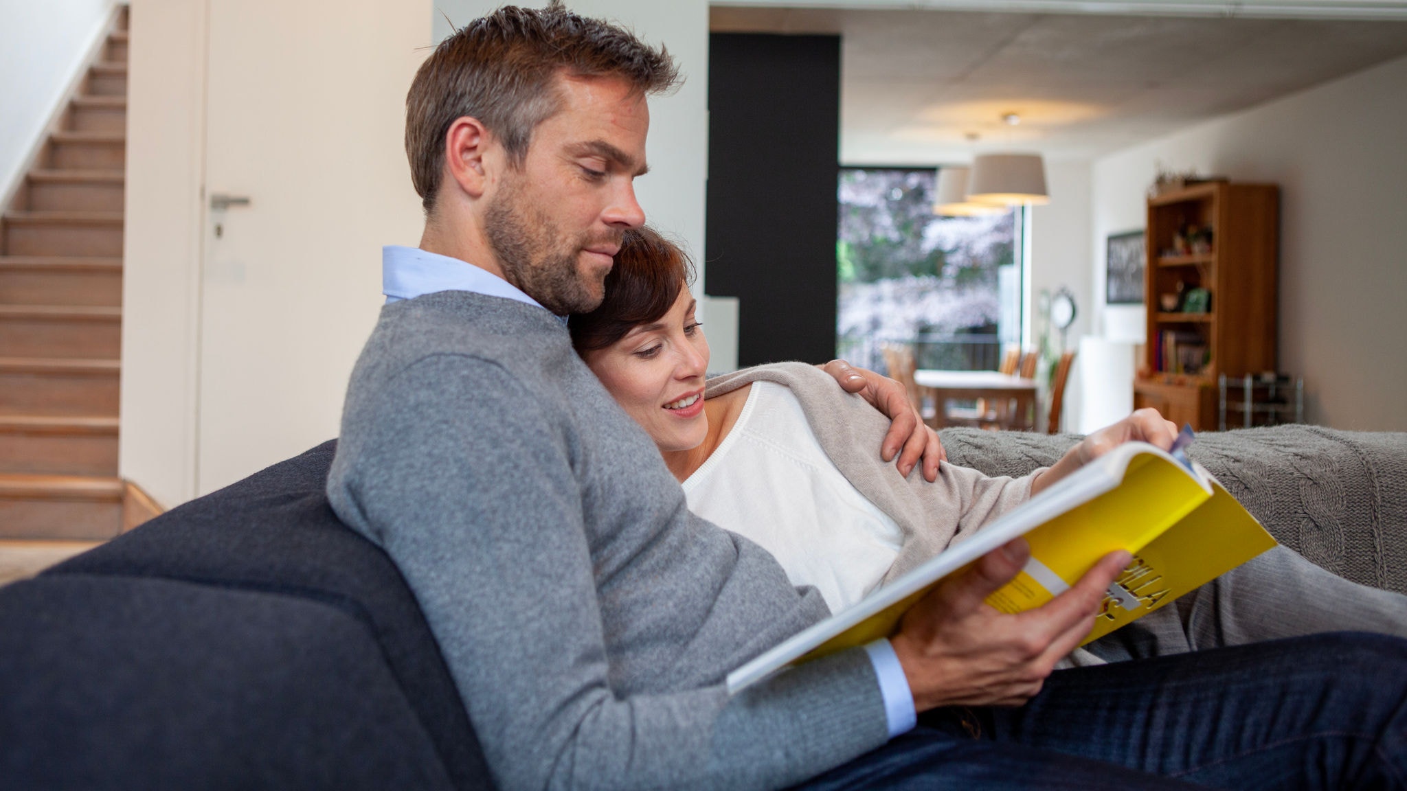 Cuplu care se relaxează și citește în interior, contând pe temperatura perfectă datorită aparatului de aer condiționat Stylish