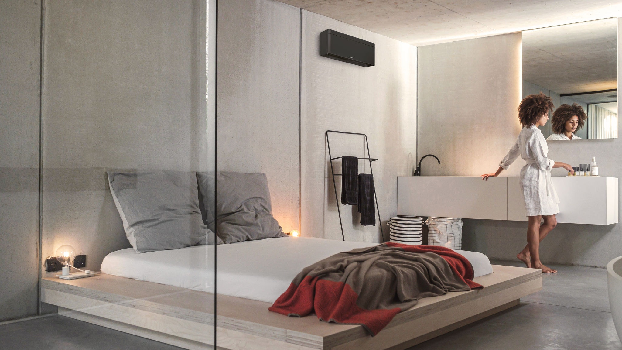 O femeie în dormitor cu un aparat de aer condiționat Daikin Stylish