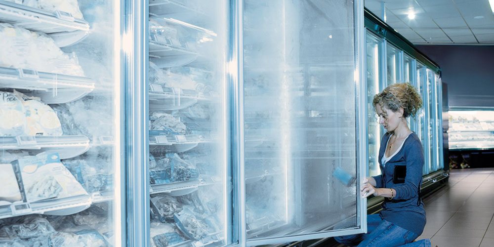 Femeie care curăță congelatoare într-un magazin alimentar